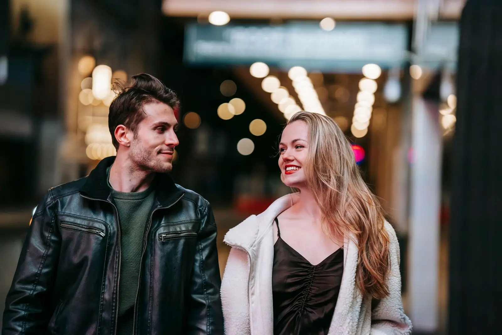 Two people walking through a city at night