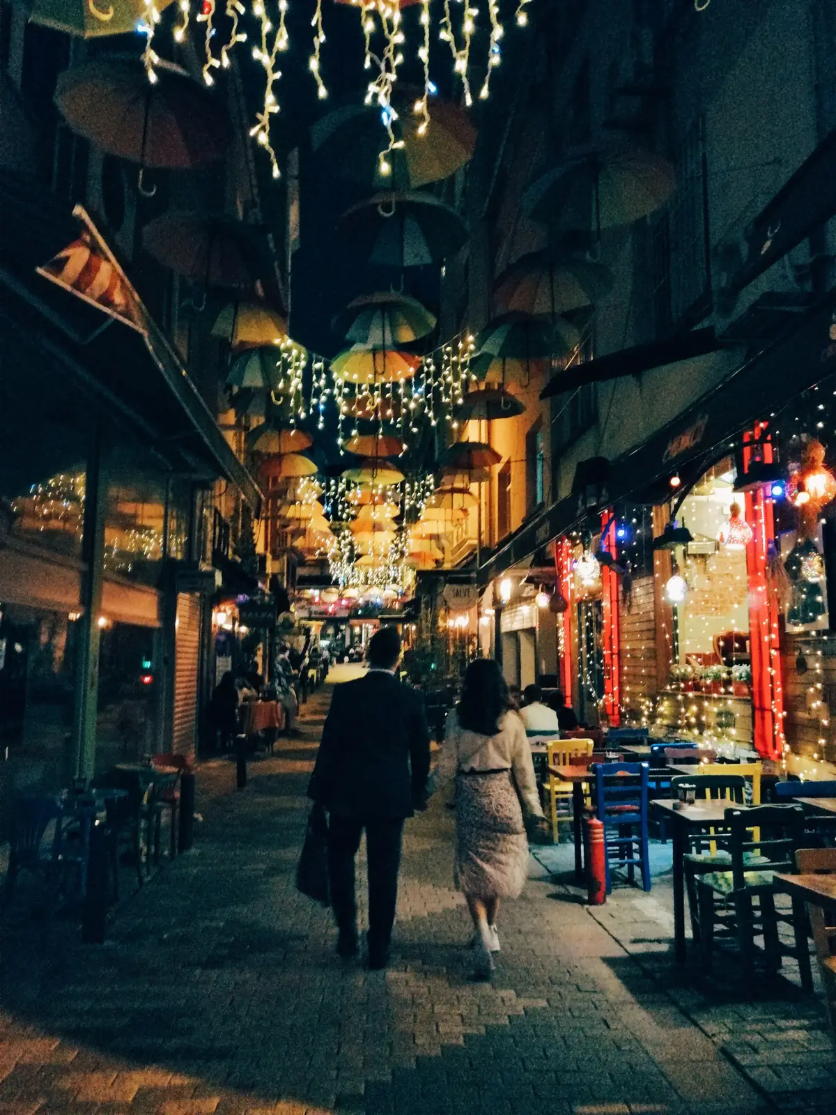 People walking down a lit street at night